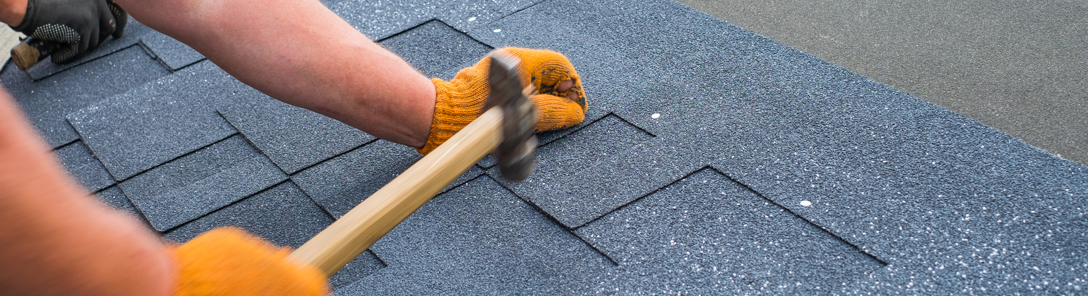 Roofer hammering in new shingles on a roof